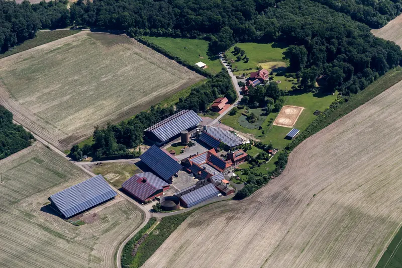 Vista dall'alto di un'azienda agricola: alcuni capannoni con i pannelli, altri con il tetto libero
